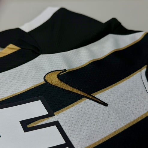 Detalhe logo Swoosh Nike dourado nova camisa infantil listrada do Galo Mineiro 2026